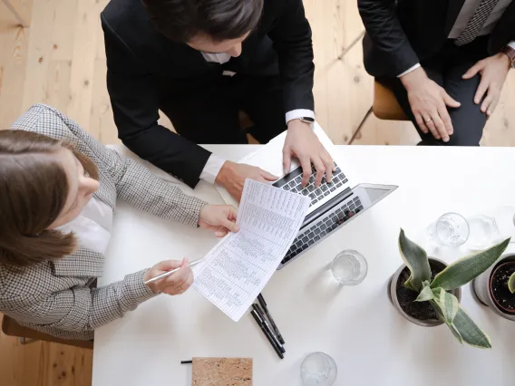 Group of individuals working on a laptop and spreadsheet